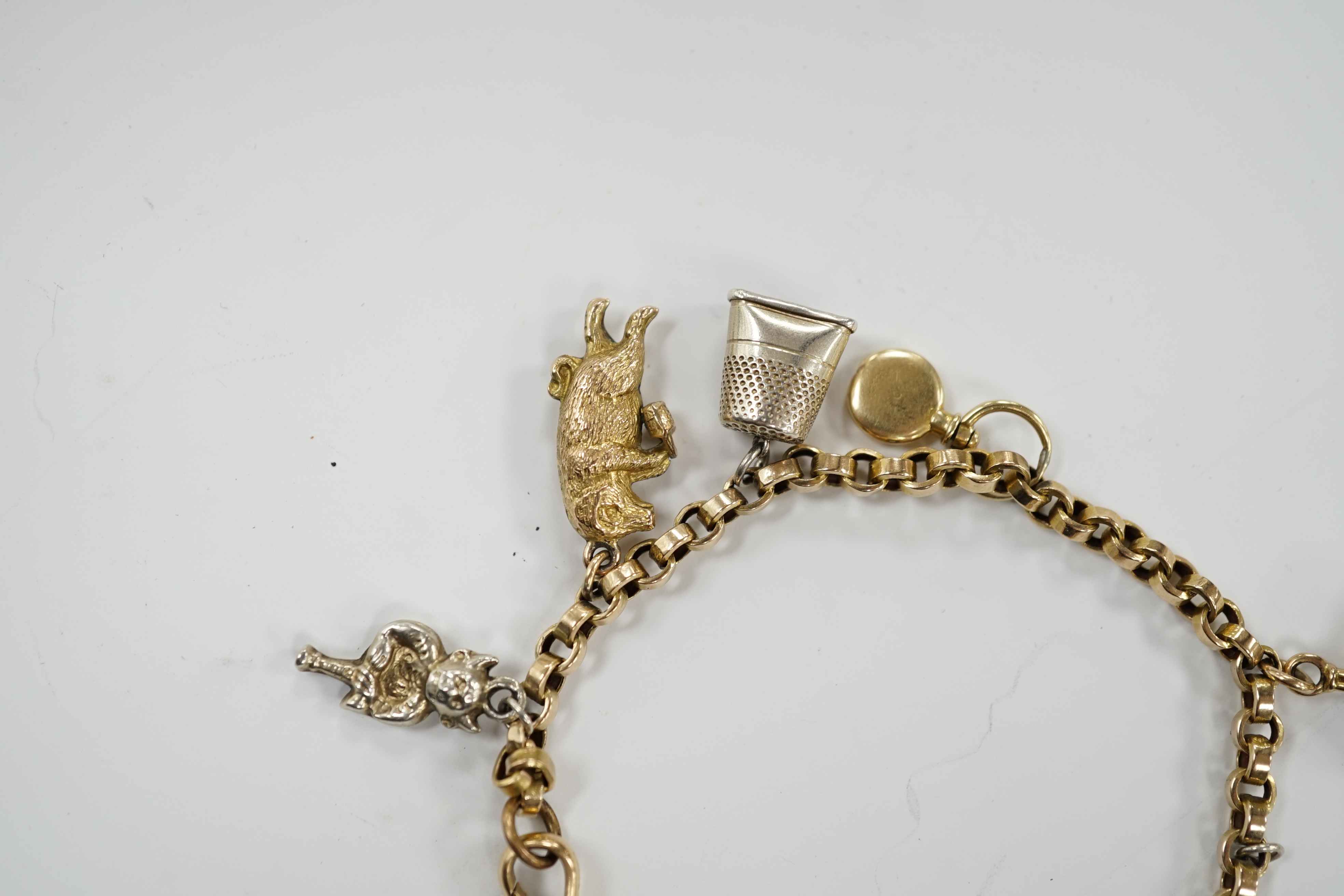 A 9ct charm bracelet, hung with nine assorted yellow and white metal charms including sterling and 10k, 16cm